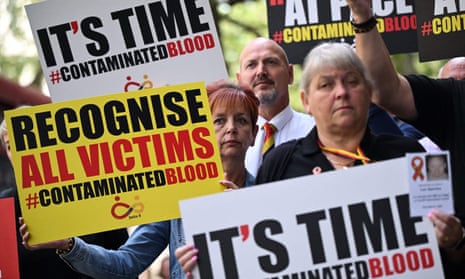 Demonstrators in July 2023 hold placards reading message related to the NHS infected blood scandal.