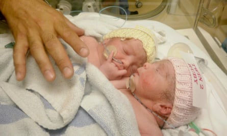 Two babies in knitted hats in an incubator