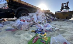 Bags of food strewn across road with vehicles behind.