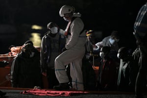 Emergency personnel assist migrants disembarking from a maritime rescue vessel in the port of Arguineguin, after their rescue off the coast of the Gran Canaria.