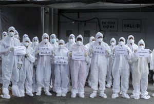 Contractual health workers in personal protective suits holds placards during a protest at the Nesco Jumbo COVID-19 center