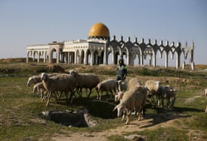 A Palestinian boy herds sheep in front of the ruins of Yasser Arafat international airport, which was bombed by Israel, at Rafah in the southern Gaza Strip