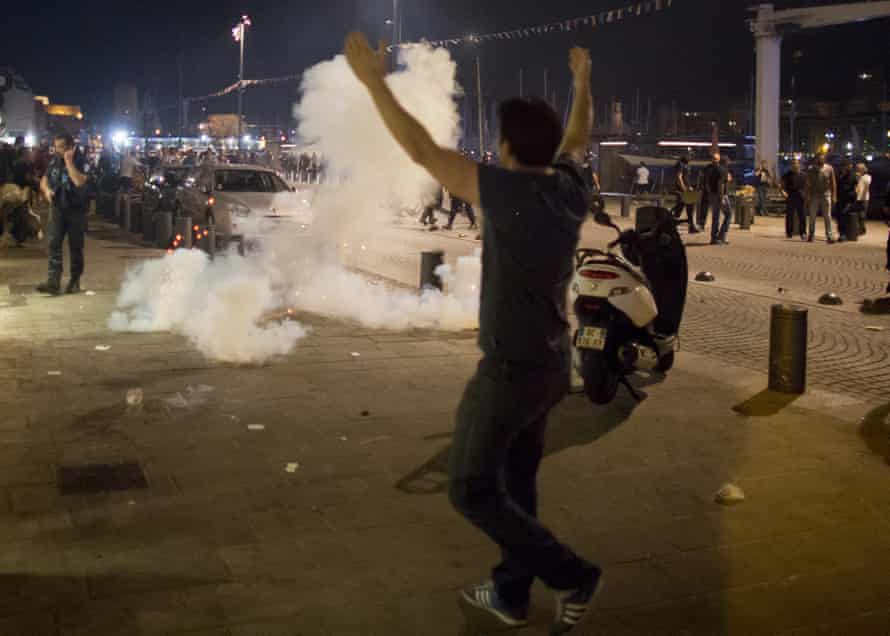 A man walks toward teargas fired by police, following scuffles in Marseille.