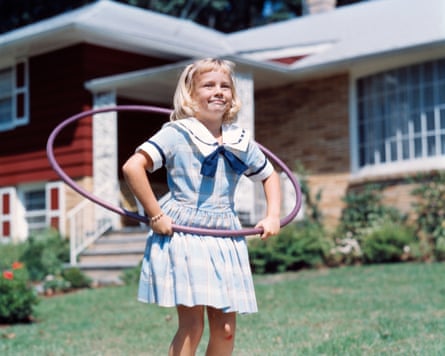 A girl playing hula hoop on a street in the 1960s.