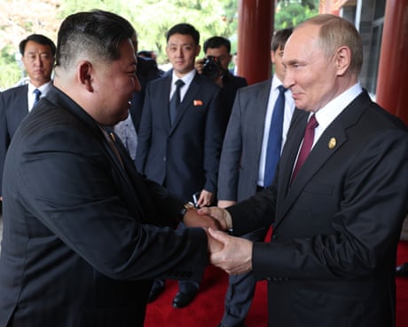Vladimir Putin grasps hands with Kim Jong-un
