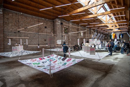 Visitors attend a preview of Catalonia in Venice: Following the Fish. Large artworks hang from a wooden-beam ceiling