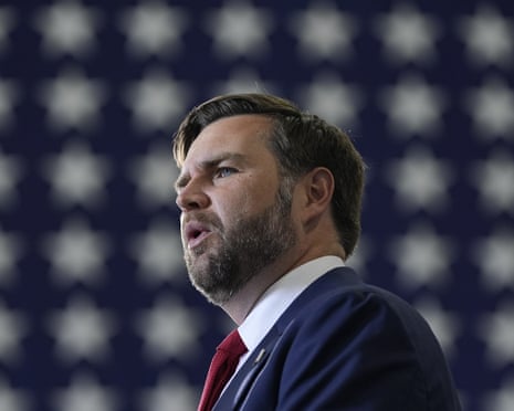 a man in a suit speaks near a US flag