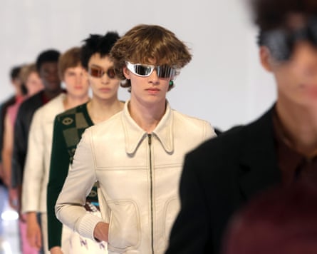 Models in a line wearing clothes that include sunglasses and a cream jacket