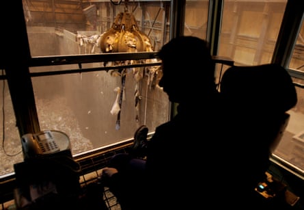 Crane operator sits silhouetted in a cab, overlooking a trash pit with a grapple