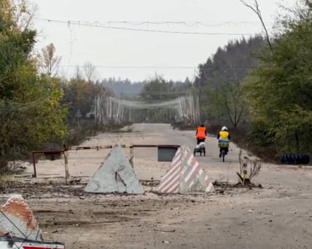 Cyclists ride past concrete barriers on a road