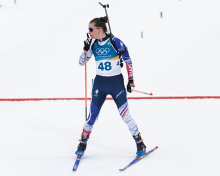 Julia Simon puts her fingers to her lips as she crosses the finish line to win the women’s 15km individual biathlon at the 2026 Winter Olympics