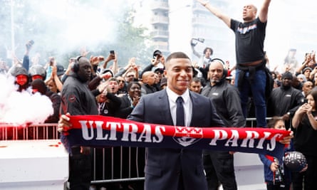 Kylian Mbappé poses with a scarf in front of fans after deciding to stay in Paris.
