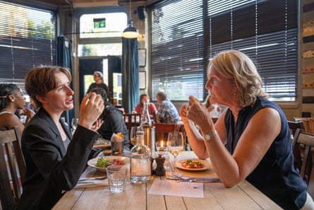 Margaret and Clare clink chat across a restaurant table
