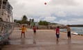 People play basketball against an abandoned boat at Anibare harbour. 