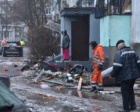 People stand among debris next to a damaged residential building following a drone attack in Dnipro amid the Russian invasion in Ukraine.
