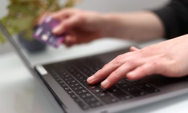 a woman using a laptop as she holds a bank card