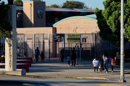 parents walk with children on a sidewalk toward a school