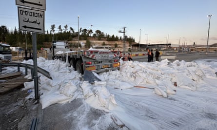 A truck with bags of flour on the road and flour covering road.