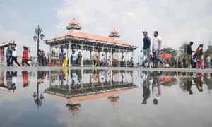 Pedestrians in Shimla reflected in a puddle. Most rainwater in the city washes away before it can be collected.
