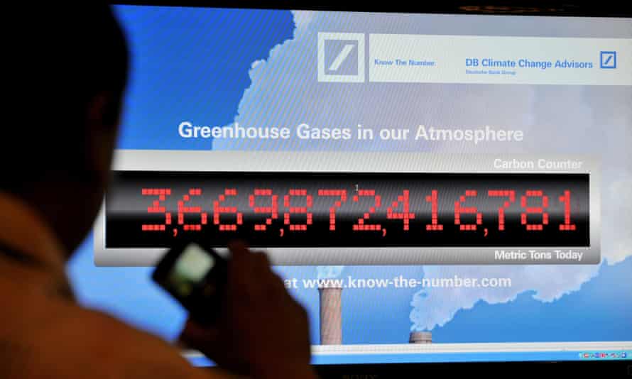 A man takes a picture of a counter showing the levels of greenhouse gases in the atmosphere