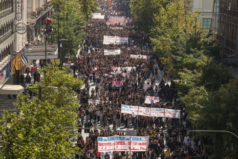 Aerial view of protesters, some carrying banners, marching down a street in Athens on a national day of protest calling for better funding into public education