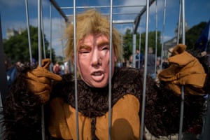 A protester dressed in a Trump mask and gorilla costume stands in a cage, London