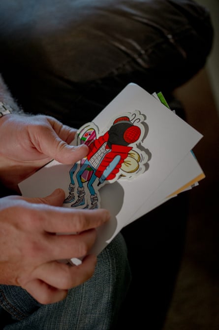 A man’s hands holding red and blue artwork on a white card