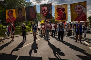 People stand in the road holding huge portraits of defenders