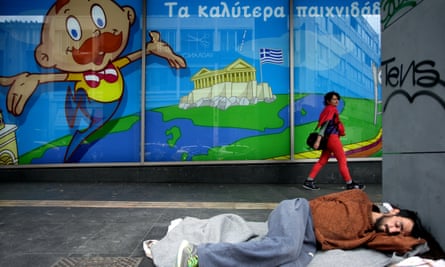 A homeless person sleeps under an image of Parthenon with the Greek flag in Athens.