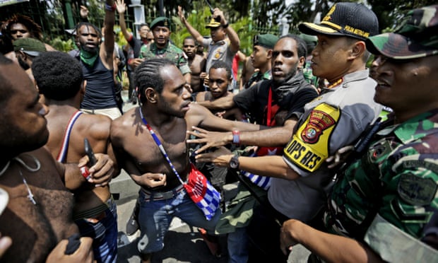 Papuan activists scuffle with police and soldiers during a rally near the presidential palace in Jakarta. President Widodo has pledged action against racial and ethnic discrimination against Papuans