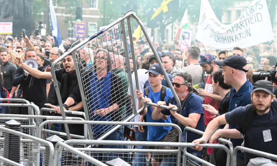 People throw fencing during an anti-vaccine and anti-lockdown demonstration outside Downing Street.