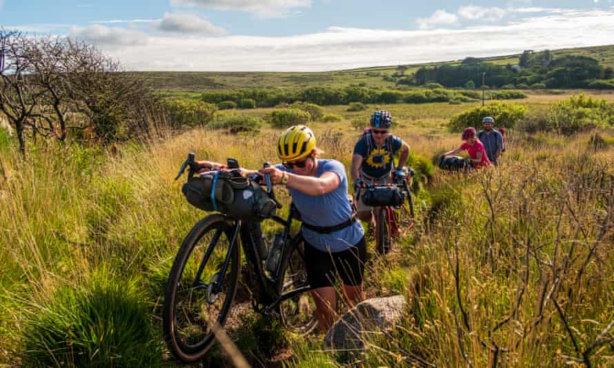 Katherine Moore (unpaved podcast), Rob Penn (freelance journalist), Sophie Gordon (Cycling UK) and Stefan Amato (Pannier) push their bikes along a difficult and overgrown track through the Penwith Moors during a reconnaissance hike on Cycling UK's West Kernow Way. , June 2021. The 230 km route is part of the EU funded EXPERIENCE project to develop sustainable tourism activities all year round in Cornwall.