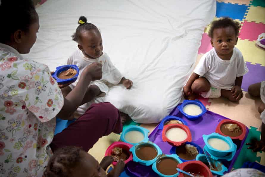 Metelus Anouse alimenta a Dorine, de 10 meses, en la guardería de la fábrica textil Codevi, donde trabaja la madre de Dorine, Geralda.