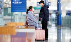 People wear face masks while waiting on the platform of the Airport Express train at Beijing Capital Airport