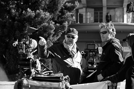 John Irvin on set with a crew member, pointing, with a film camera in the foreground