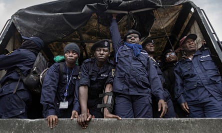 Police officers in uniform look out from the back of a truck