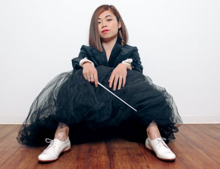 Elim Chan sits on the floor against a wall, holding her baton.
