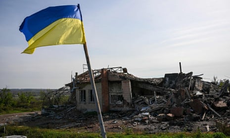 A Ukrainian national flag is displayed in front of a destroyed house near Izyum, eastern Ukraine.