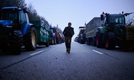 A French farmer walks past tractors as they block the A16 highway south of Beauvais towards Paris.
