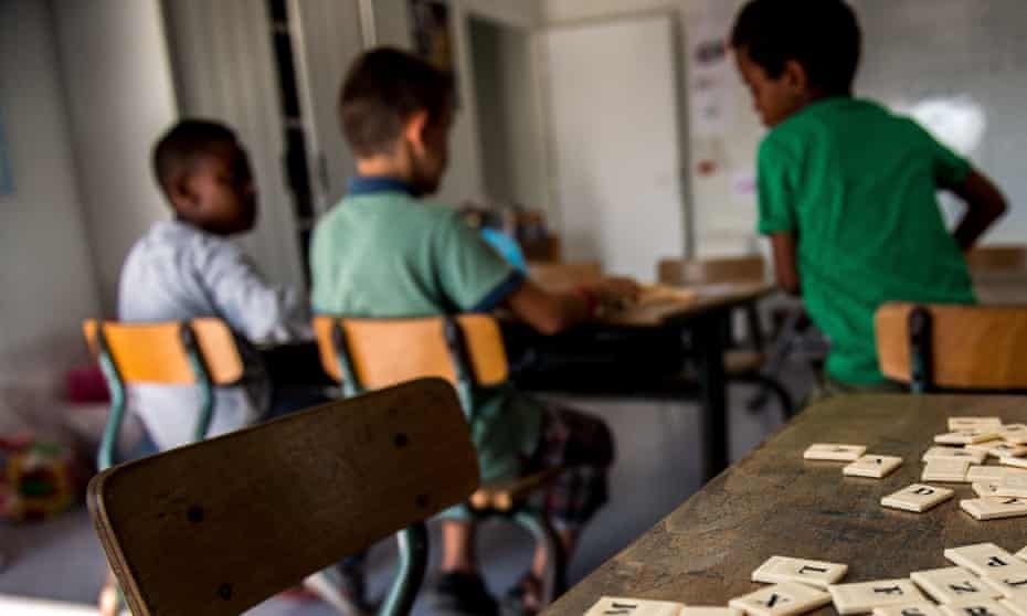 Three migrant children sit together in a classroom