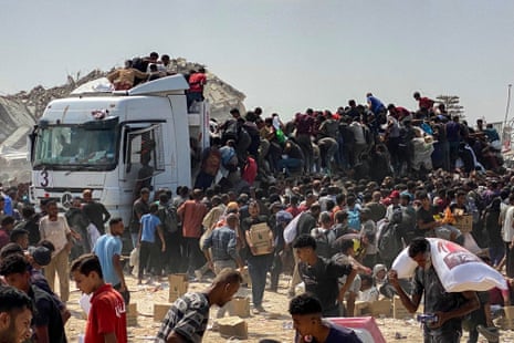 Desperate Palestinian people carry food parcels as they raid trucks carrying humanitarian aid in Khan Younis.