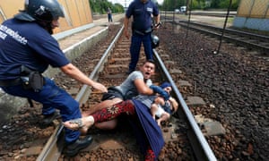 A family lies on tracks at Bicske station after a train bound for the Austrian border was stopped by police