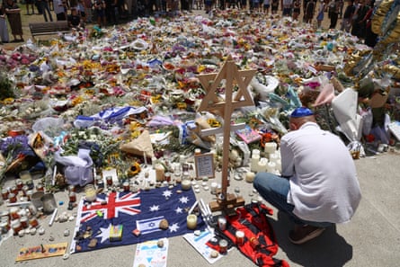 A mourner lights candles next to floral tributes at Bondi Pavilion after the December attack
