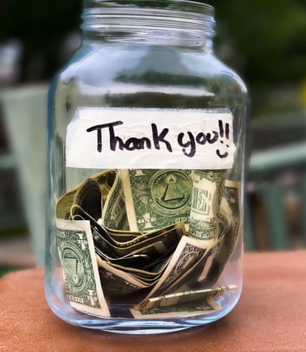 A glass jar full of dollar bills, with a sticker with the words ‘thank you!!!’
