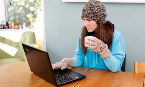Picture of woman working from home, wrapped up in warm clothing, at a laptop