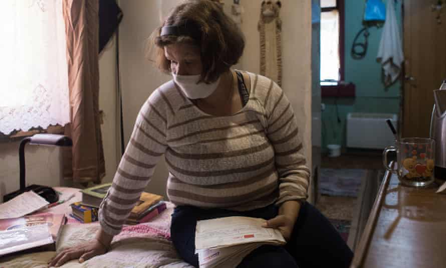 Tetiana Shulzhynska goes through her medical records at her home in Chernihiv, northern Ukraine