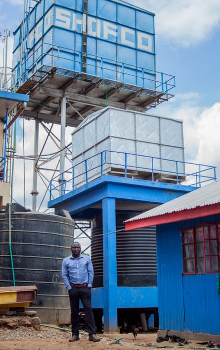 Kennedy Odede next to the water tower built by Shofco, which runs an aerial water pipe across the slum, bringing clean water to people living nearby. Kibera, Nairobi.