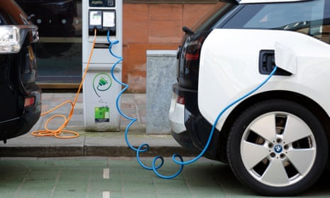 Two electric cars charging on a city street.