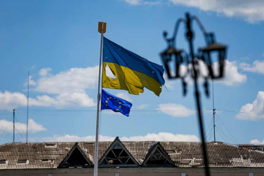 flag of Ukraine ripped as a result of Russian shelling flies next to an EU flag in the central square of Malyn, Zhytomyr.