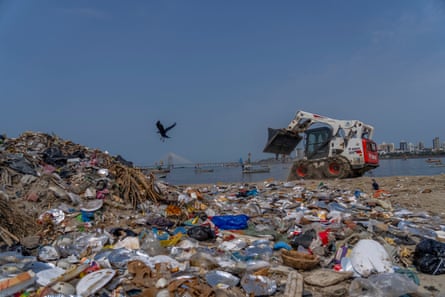 A mini excavator cleans up plastic and other waste on a beach in Mumbai, India.